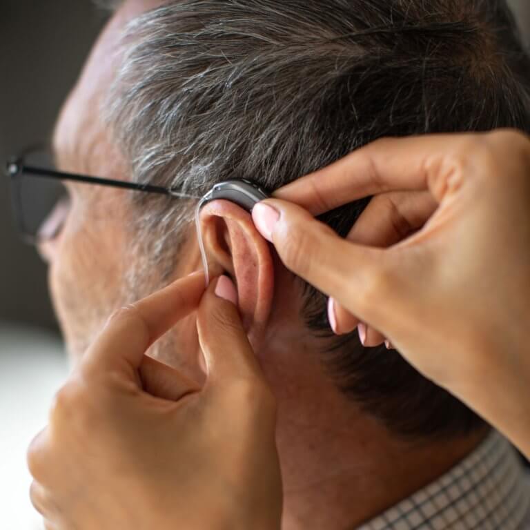 Close up shot of an audiologist fitting hearing aids.