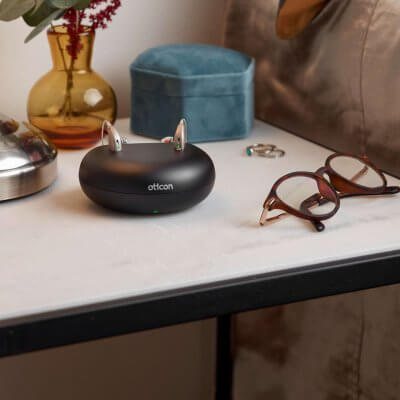 A pair of hearing aids Oticon Opn in a charging doc on a bedside table.