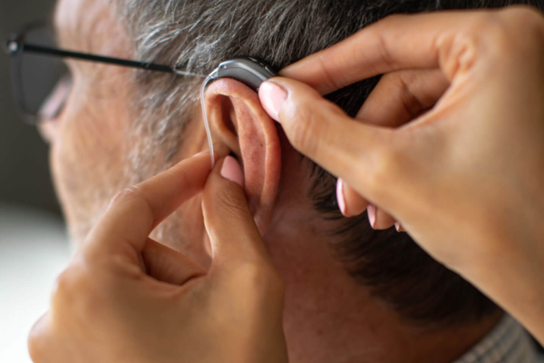 An audiologist fitting a hearing aid in a patient's ear.