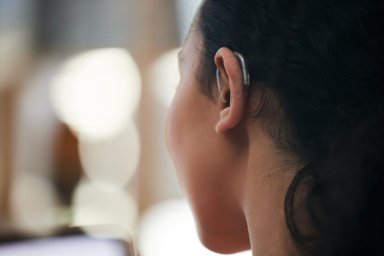 A girl wearing a hearing aid and watching something on a screen.