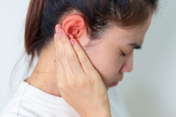 A woman holding her red and inflamed ear.