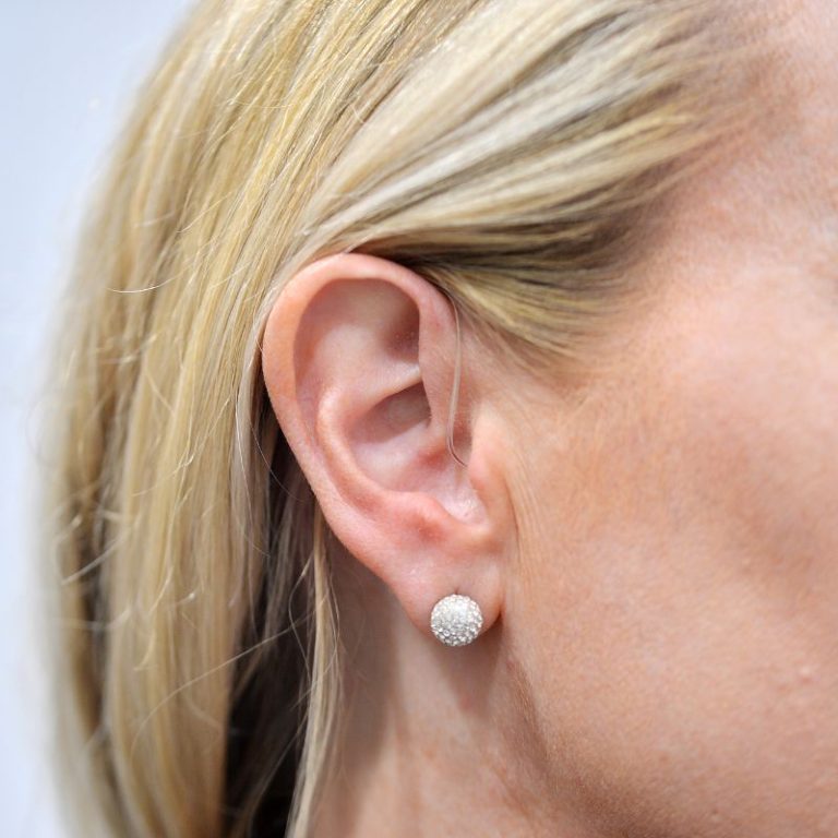 Close-up of a woman wearing Receiver In Canal (RIC) hearing aids.