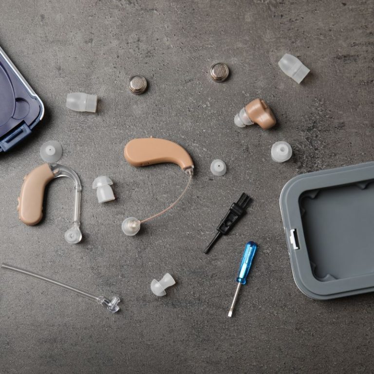 A collection of hearing aid maintenance tools, including cleaning brushes, wax removal tools and hearing aids.