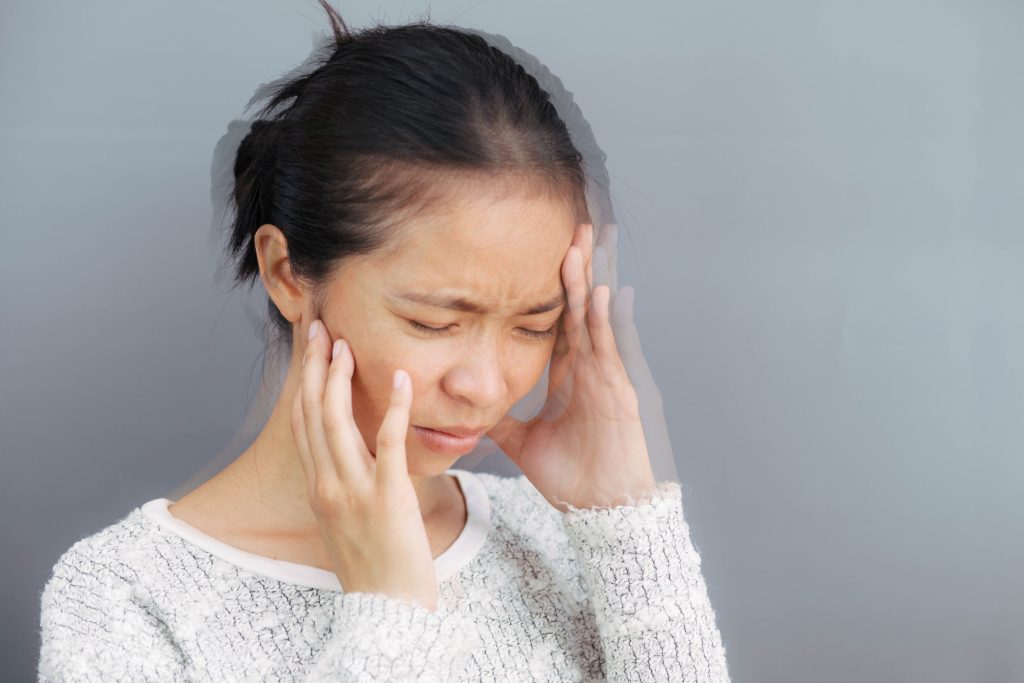 A woman experiencing vertigo, appearing disoriented and unsteady.